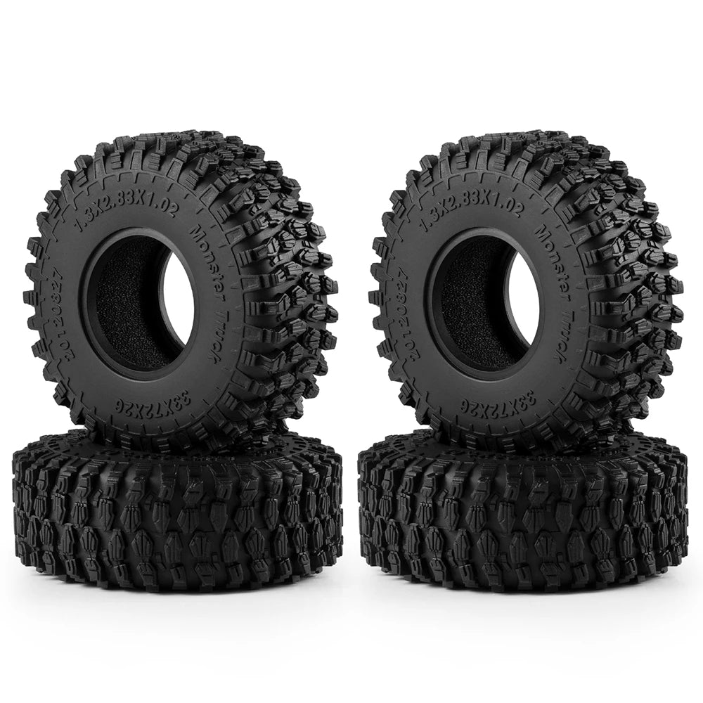 A set of four black mud terrain rubber tires for RC crawlers, stacked on a white background.