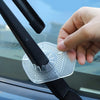 A hand is installing a clear plastic protective cover over a car windshield wiper blade.