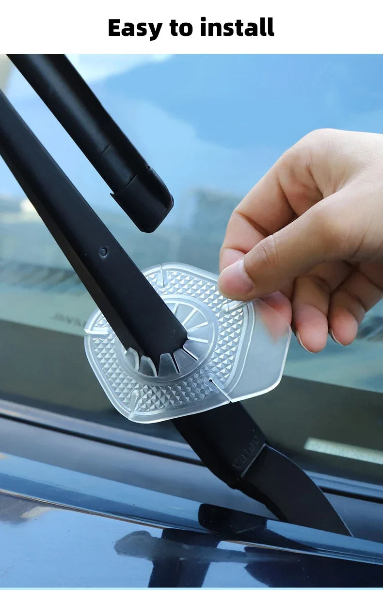 A hand is installing a clear plastic protective cover over a car windshield wiper blade.