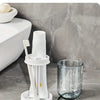 A white modern bathroom toothbrush holder with a dust cover and drainage, placed on a marble countertop.