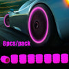 Eight luminous pink tire valve caps with a glow-in-the-dark design shown in a close-up on a car wheel.