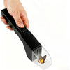 A hand is holding a black handheld insect catcher with a clear plastic collection chamber.