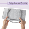Hands holding a gray collapsible and portable canvas diaper storage organizer.