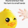 A yellow wind-up bath toy duck with a smiling face is shown next to a hand.