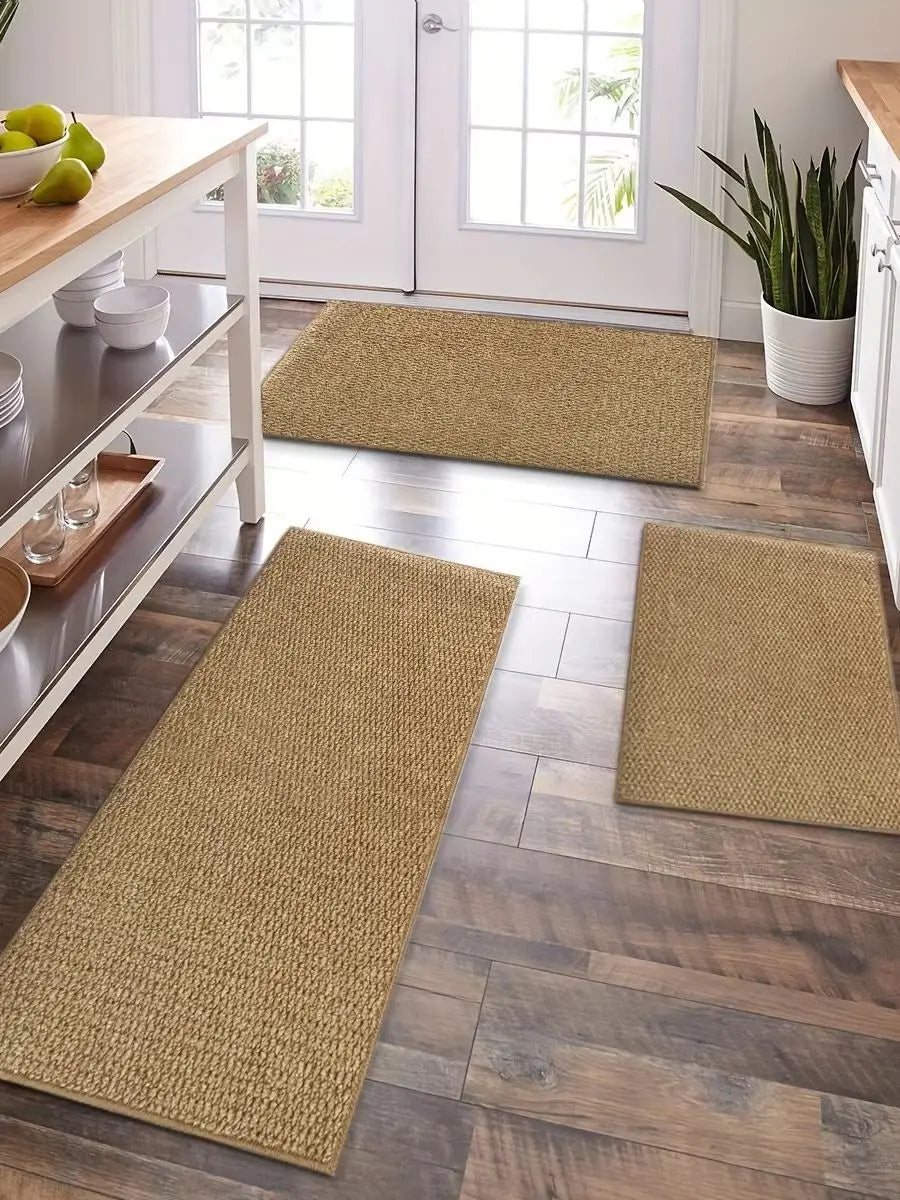 A row of natural fiber kitchen runner rugs in beige and tan are laid out on a light wood floor near a window.