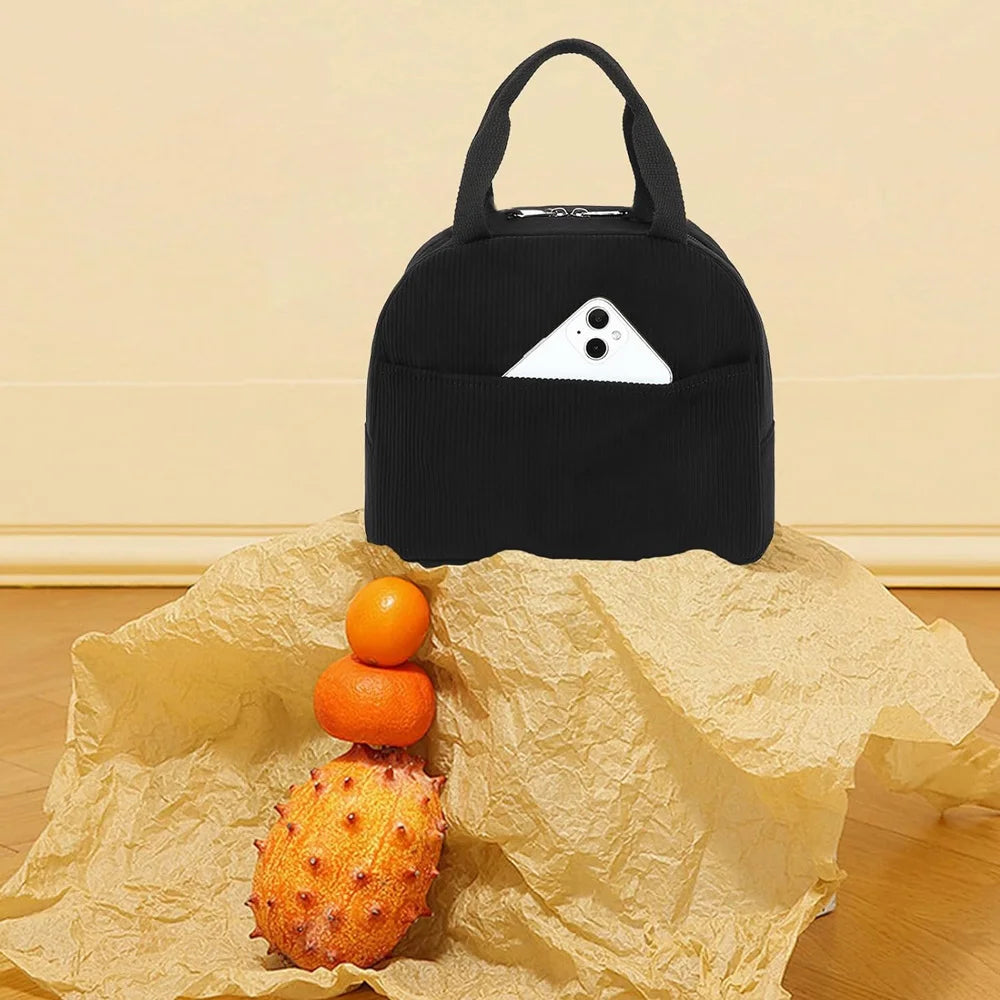 Black embroidered corduroy insulated lunch bag with a triangular white design resting on crumpled brown paper.