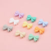 A collection of pastel silicone crown beads in lavender, mint green, pale yellow, and light blue scattered on a pink backgrou