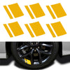 A set of six yellow reflective stickers placed on a car wheel hub.