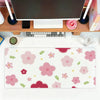 A pink floral mouse pad with various colored flowers and leaves placed on a wooden desk next to a laptop.