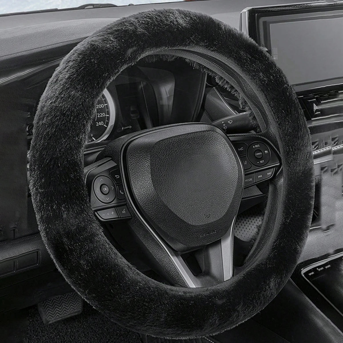 Close-up view of a black winter plush steering wheel cover on a car interior.