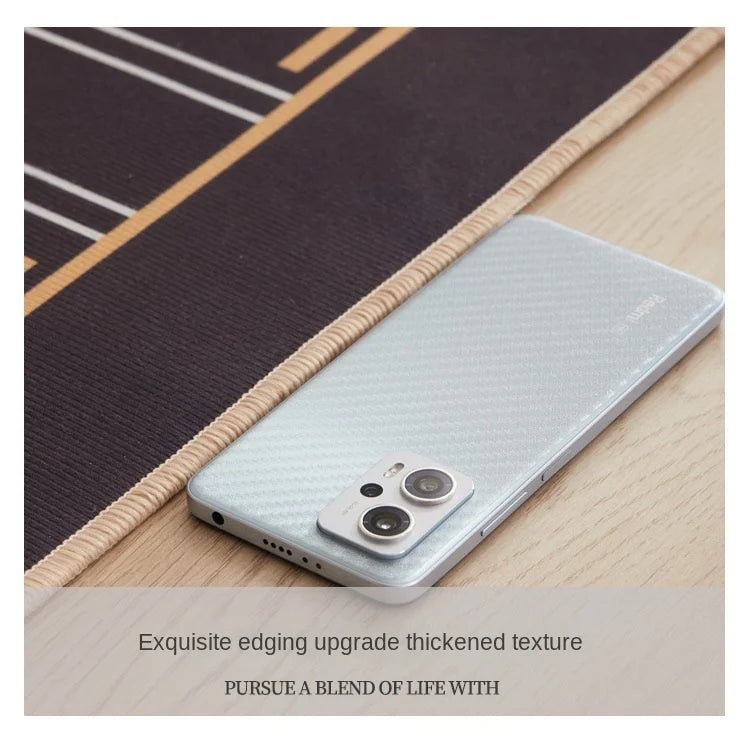 Silver smartphone placed on a dark mat with light wood background.