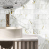 A modern bathroom vanity featuring a white vessel sink and marble-patterned wall tiles.