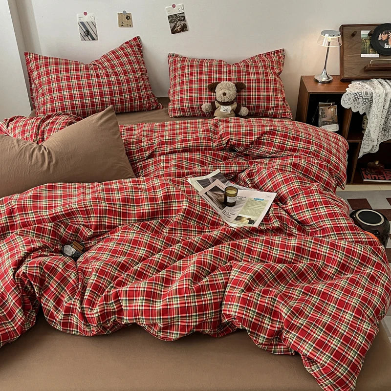A red and green plaid duvet cover set with matching pillows and a decorative stuffed animal on a bed.