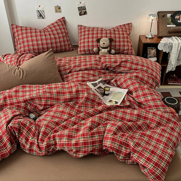 A red and green plaid duvet cover set with matching pillows and a decorative stuffed animal on a bed.