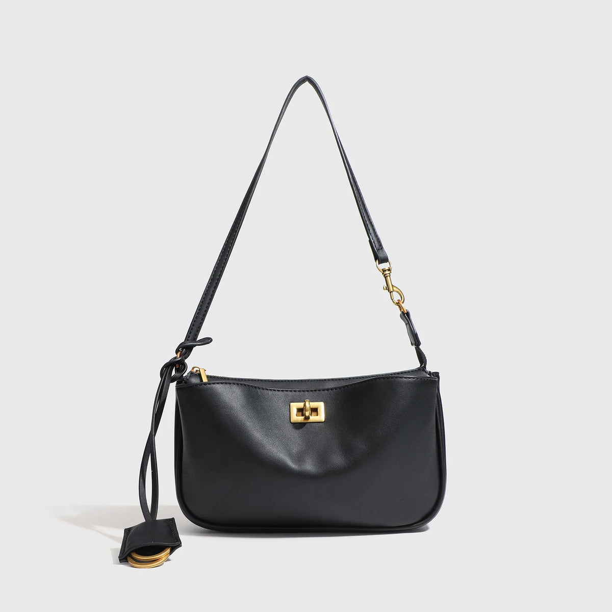 A black leather tote bag with a gold-toned metal buckle and long strap.