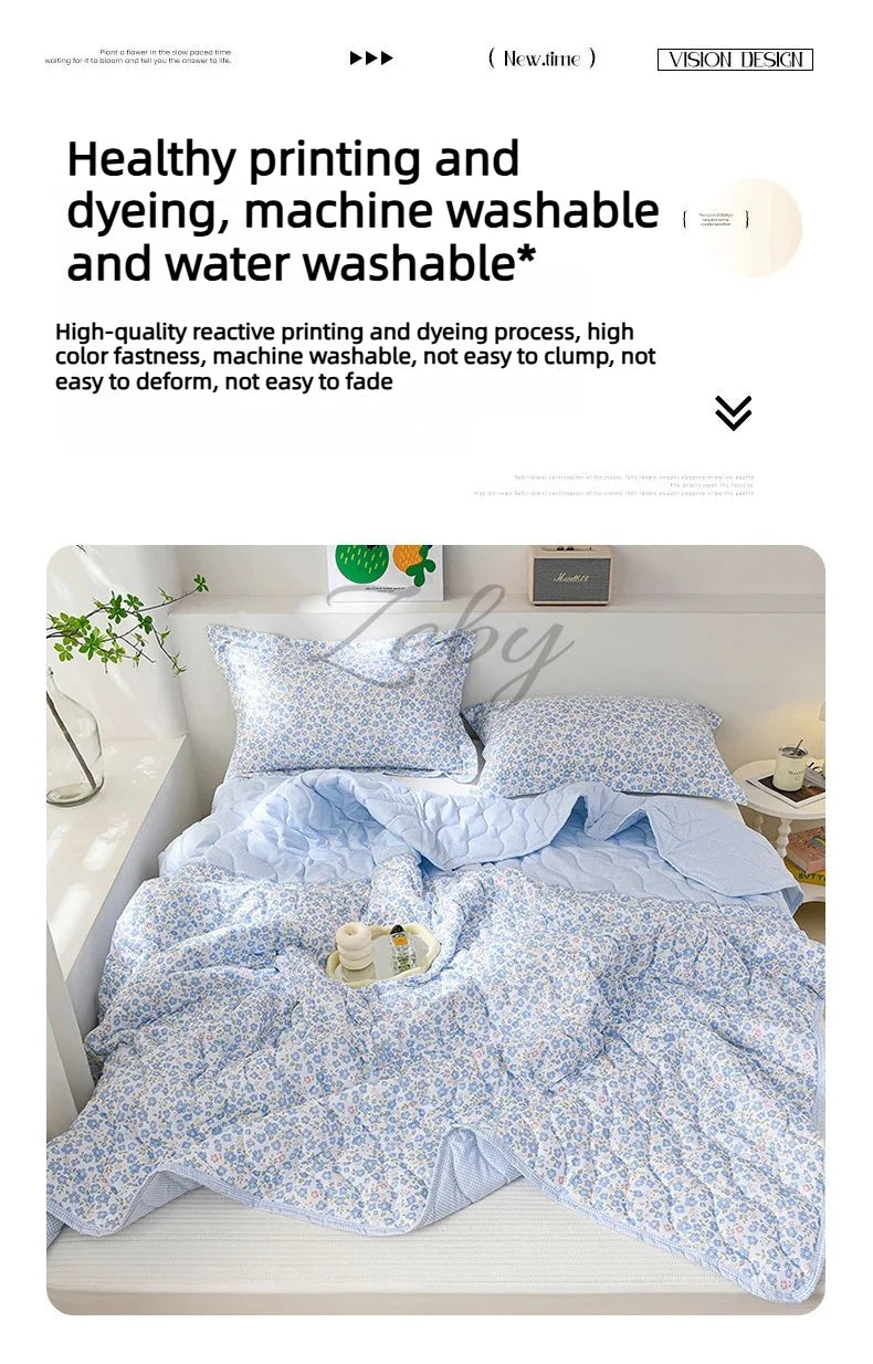 A light blue floral quilted blanket is displayed on a bed, showing its soft texture and pattern.