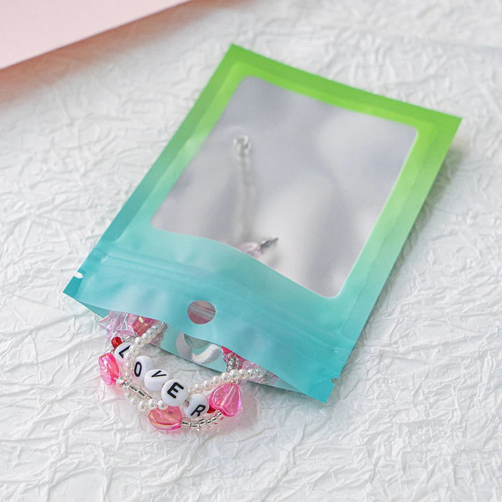 A clear window ziplock pouch containing a delicate pearl and pink flower necklace on a white surface.
