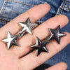 Silver star-shaped metal belt buckle or brooch pin shown on a hand against a denim background