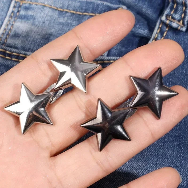 Silver star-shaped metal belt buckle or brooch pin shown on a hand against a denim background