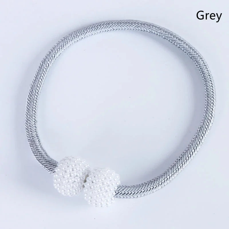 A silver-toned magnetic curtain clip made of twisted wire, shown against a white background.