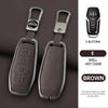 A pair of brown leather key case covers with metal keychains and a black electronic remote control.