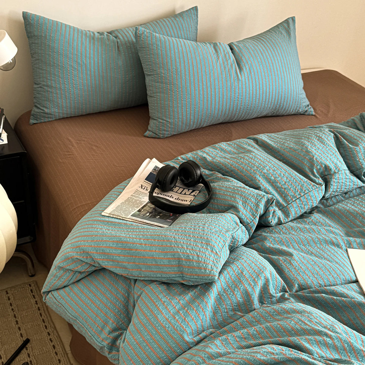 A teal and beige striped duvet cover set with matching pillowcases on a bed.