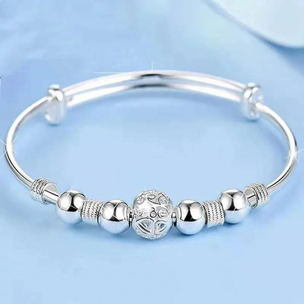 Bracelet à perles argenté pour femmes, présenté sur fond bleu clair.