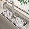 A modern chrome faucet mounted on a square white mat with black grid lines, set in a bathroom sink.