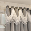Gray sheer curtains with white lace trim are hung on a rod in a room.