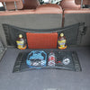 A black mesh car seat back organizer with orange and yellow storage compartments is shown in a vehicle interior.