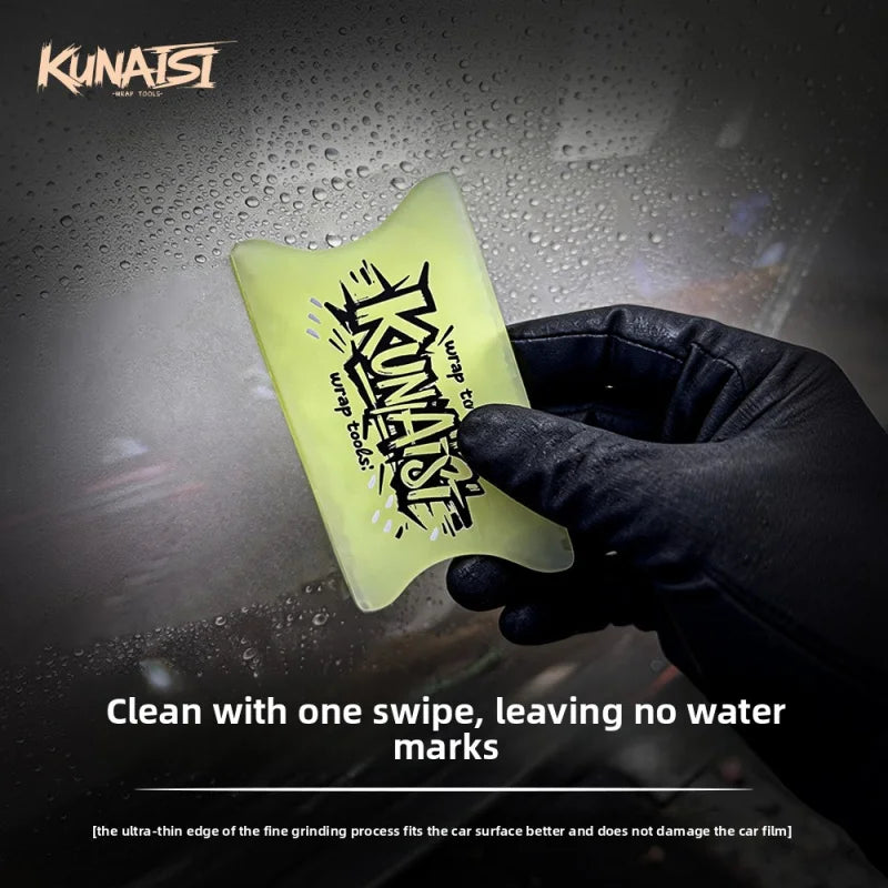 A hand is holding a yellow TPU car wrap film squeegee against a dark background with water droplets.