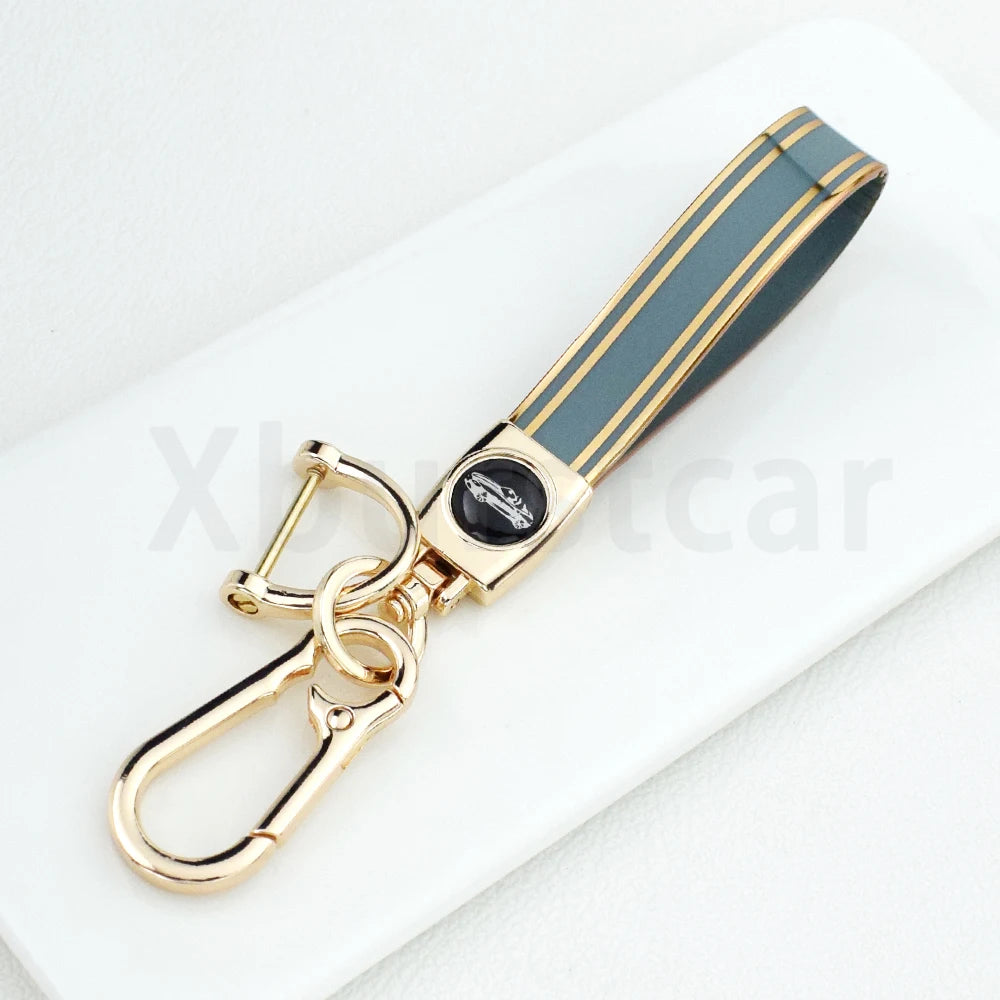 A gold-toned TPU key fob cover with a black and gray striped design resting on a white surface.