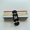 A black fingerboard ramp set with a quarter pipe and rail rests on a wooden box.