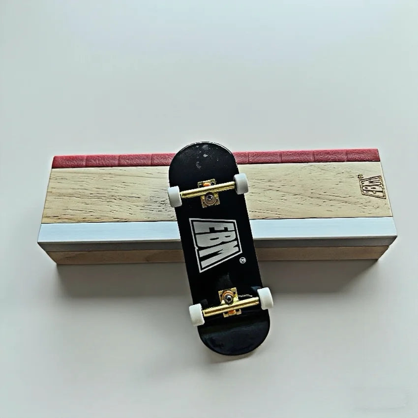 A black fingerboard ramp set with a quarter pipe and rail rests on a wooden box.