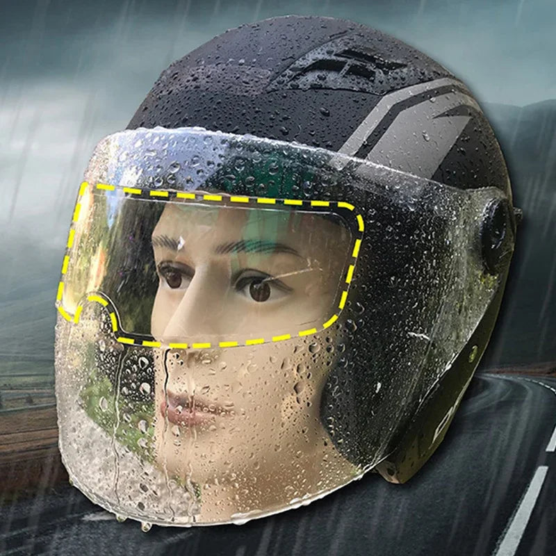 A close-up of a motorcycle helmet with an anti-fog and rain shield film covering the visor, showing water droplets.