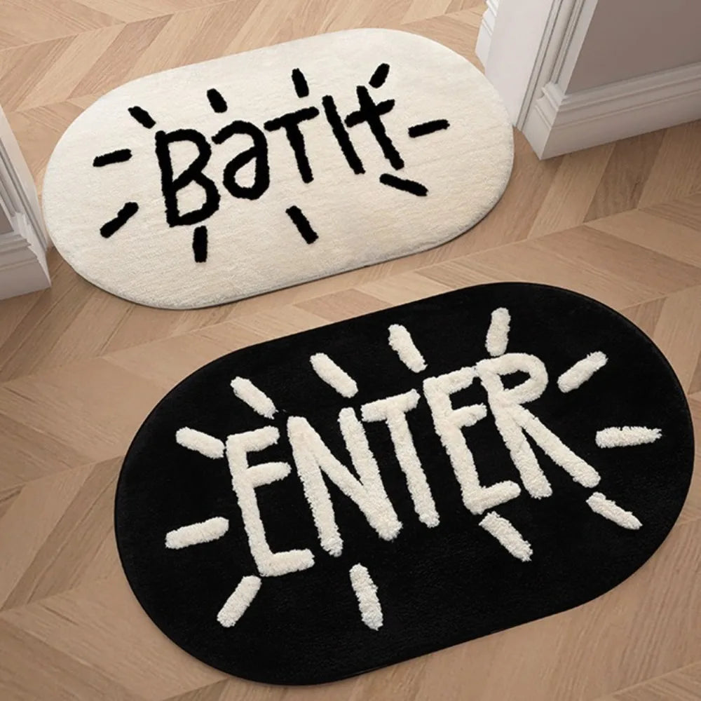 A black bath mat with white text that reads ENTER is placed on a light wooden floor.