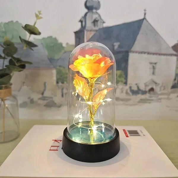 LED-Rosen-Nachtleuchte in einer Glühbirne beleuchtet eine gelbe Blume vor unscharfem Hintergrund von Gebäuden.