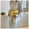 A woman holds a gold crocodile pattern PU envelope clutch with a coin pocket in front of a white cabinet and mirror.