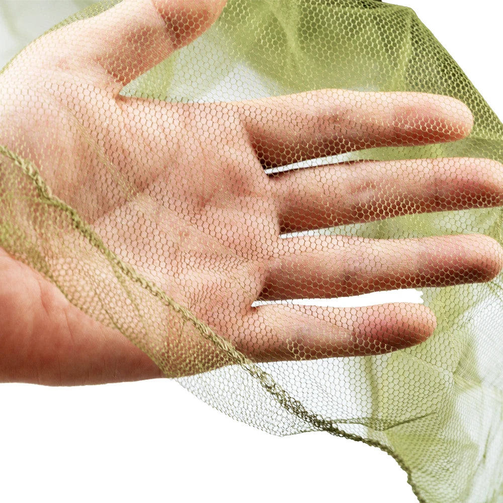 A hand is holding a sheer, light green mosquito net fabric.
