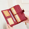 A maroon leather bifold wallet with a zip-around closure and wristlet strap is shown open, displaying several cards.