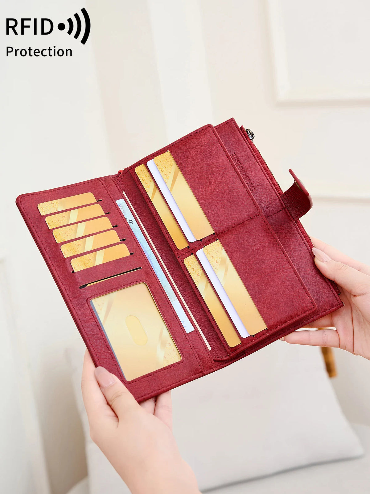 A maroon leather bifold wallet with a zip-around closure and wristlet strap is shown open, displaying several cards.