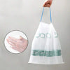 A hand holds a large white drawstring trash bag with handles, showing several scented bags inside.