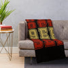 A knit throw blanket featuring the NFL 49ers logo in red, gold, and black on a gray sofa.