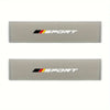 A pair of beige soft car seat belt cushions featuring the Sport logo in black and orange.