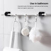 White adhesive curtain rod hooks mounted on a wall, holding bath towels, balls, and brushes.