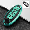 A teal TPU key fob cover with a black grip and multiple buttons is shown resting on a black textured surface.