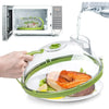 A hand holds a green microwave splatter cover with a steamer and ergonomic handle over a plate of food.