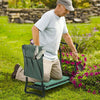 An elderly man kneeling on a heavy duty foldable garden kneeler seat with a tool pouch in a grassy garden.