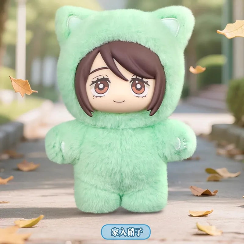 A soft green cat plush doll with a hood and human-like face is displayed outdoors on a wooden surface.