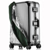 A silver suitcase with a transparent green waterproof cover draped over it.